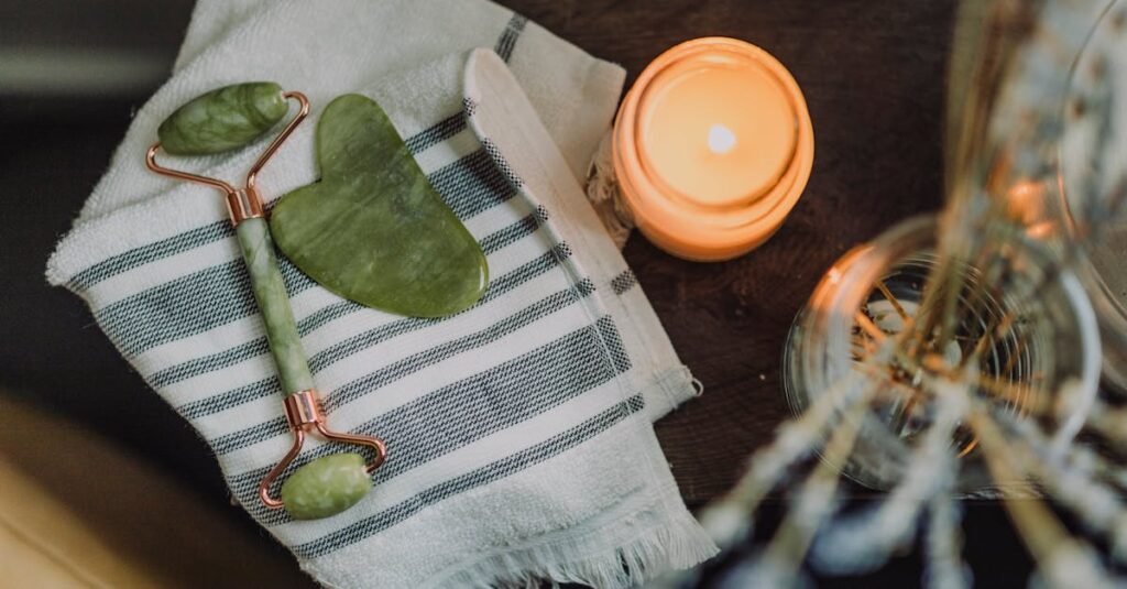 A serene spa setup featuring a jade roller, gua sha, towel, and candle for ultimate relaxation.