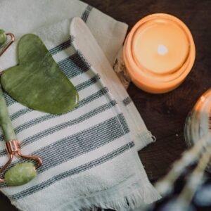 A serene spa setup featuring a jade roller, gua sha, towel, and candle for ultimate relaxation.
